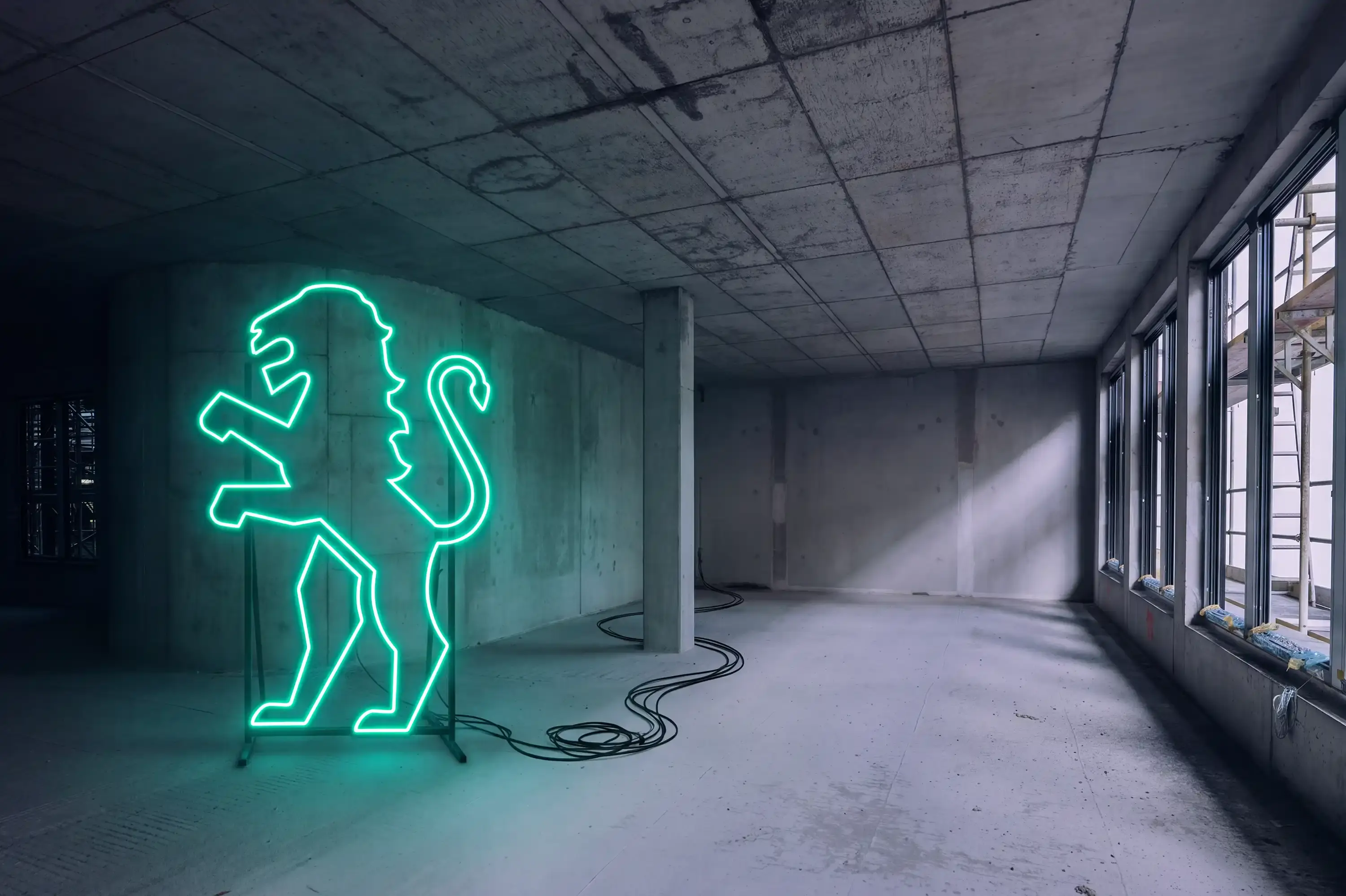 Löwe der Marke Becken als grüne Neonleuchte in einem Rohbau