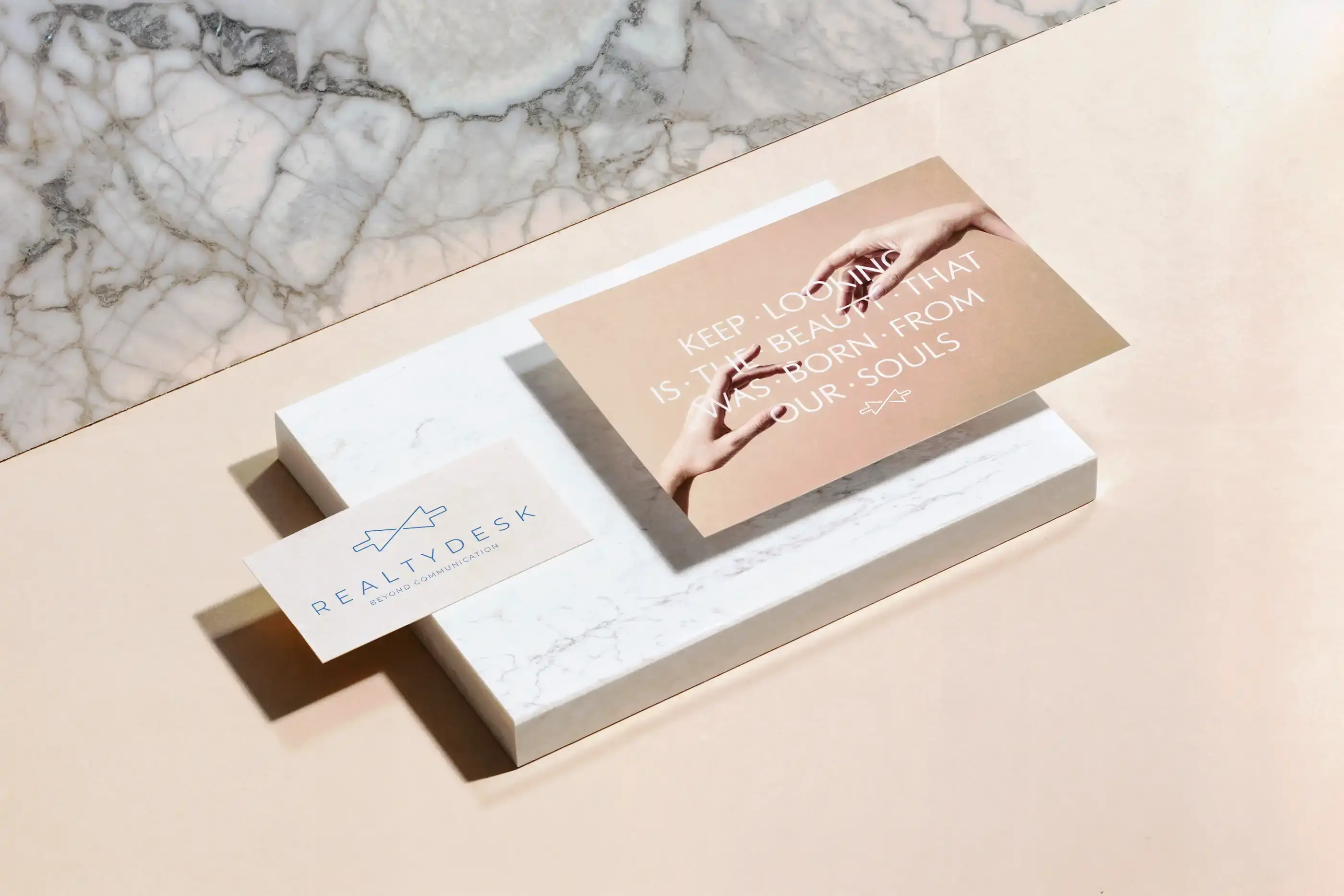 Realty-Desk-Visitenkarte und Postkarte mit zwei Händen auf einem Marmorblock vor rosa Grund