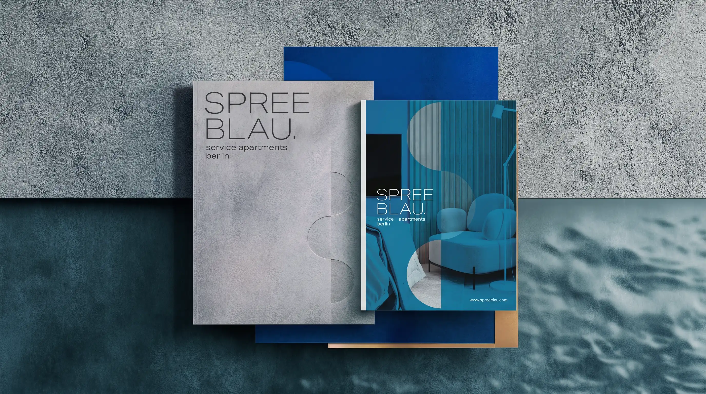 Broschüre und Mappe Spreeblau auf Betonwand und Wasserfläche